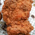 Crispy fried chicken thigh over a rack.jpg